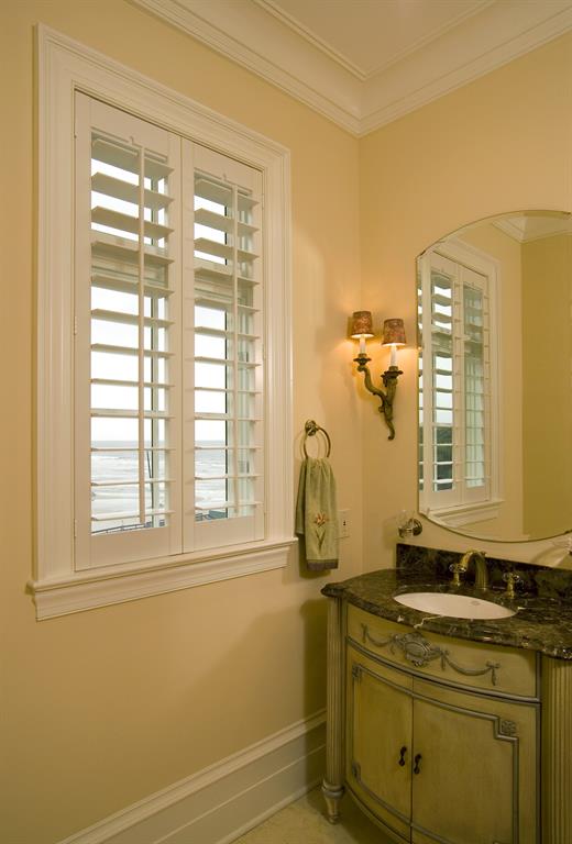 White shutters in a light bathroom give a view of the ocean